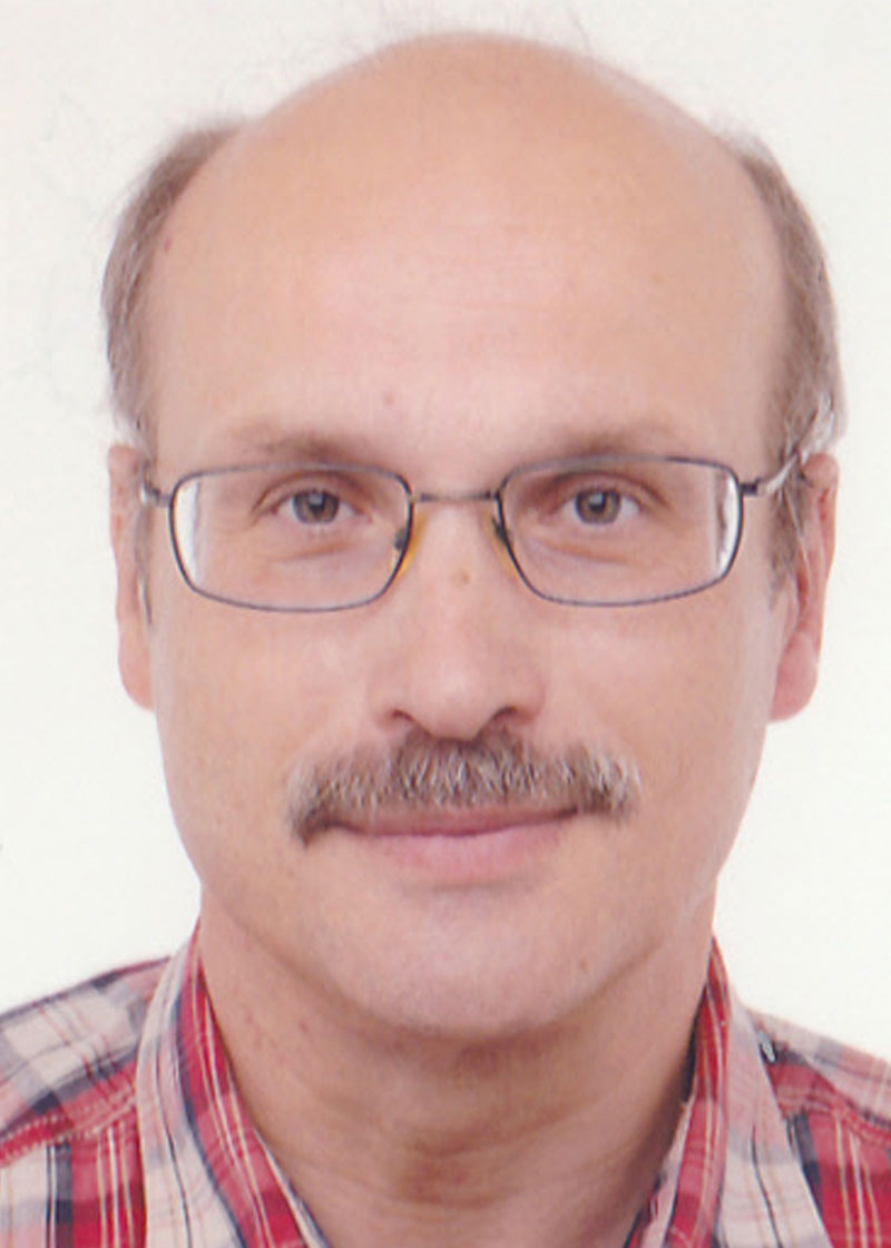 Porträt eines Mannes mit Brille und Schnurrbart.