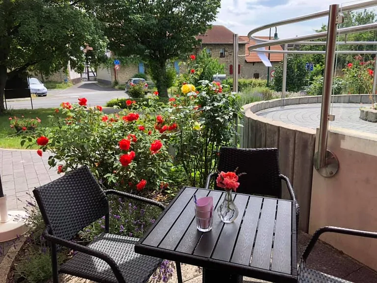 Sitzgelegenheit im Freien mit Tisch, Stühlen und roten Rosen.