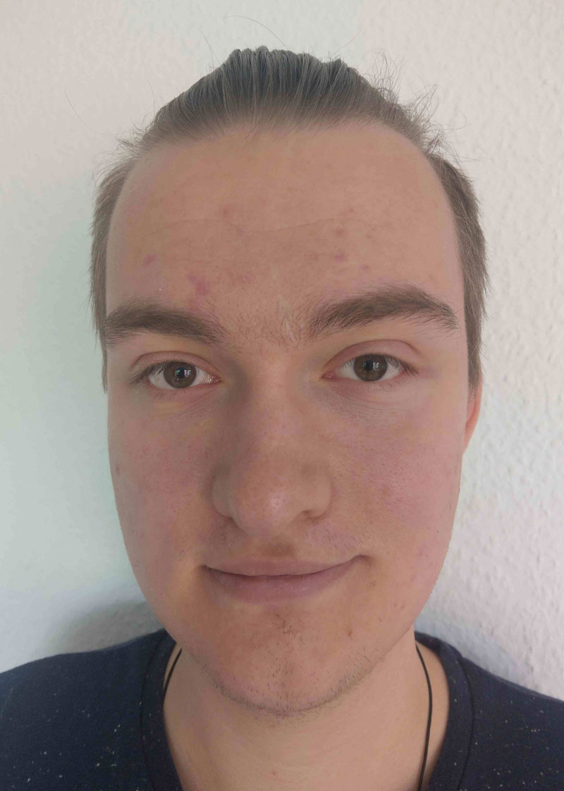 Porträt eines jungen Mannes mit zurückgebundenem Haar.