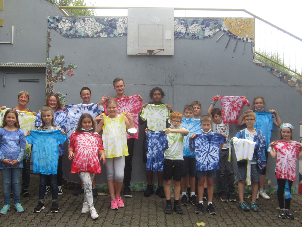 Gruppe von Kindern und Jugendlichen hält ihre Batik-Shirts hoch.