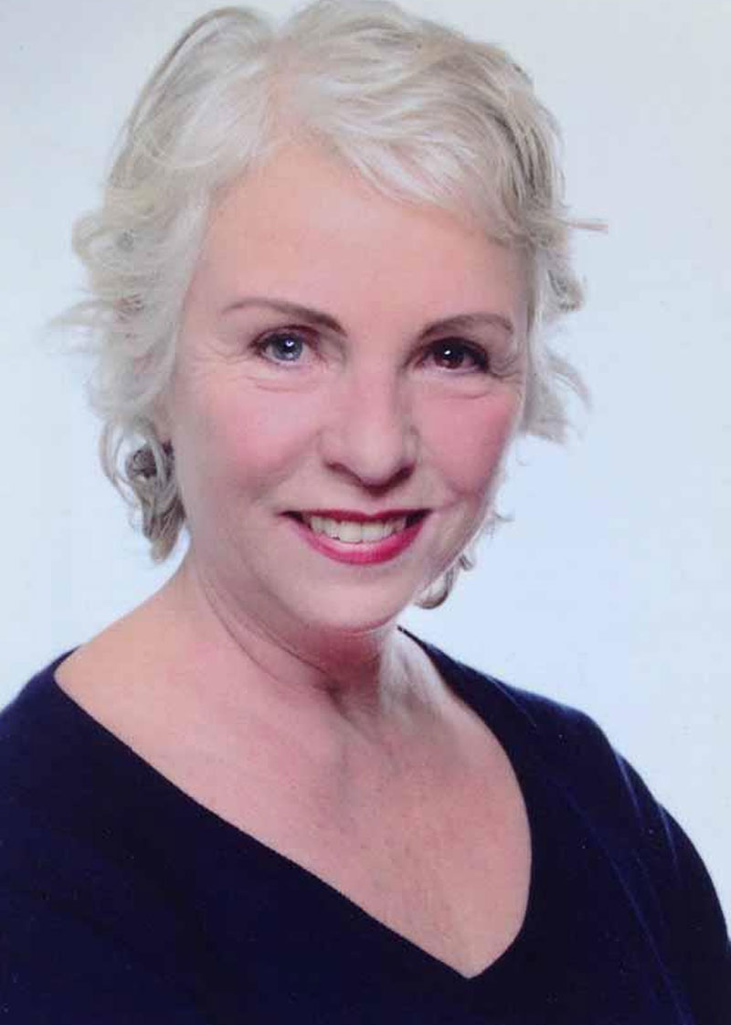 Porträt einer lächelnden Frau mit kurzem weißen Haar.